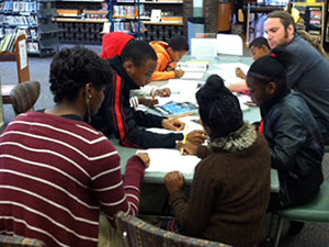 adults and children sitting around a table doing homework
