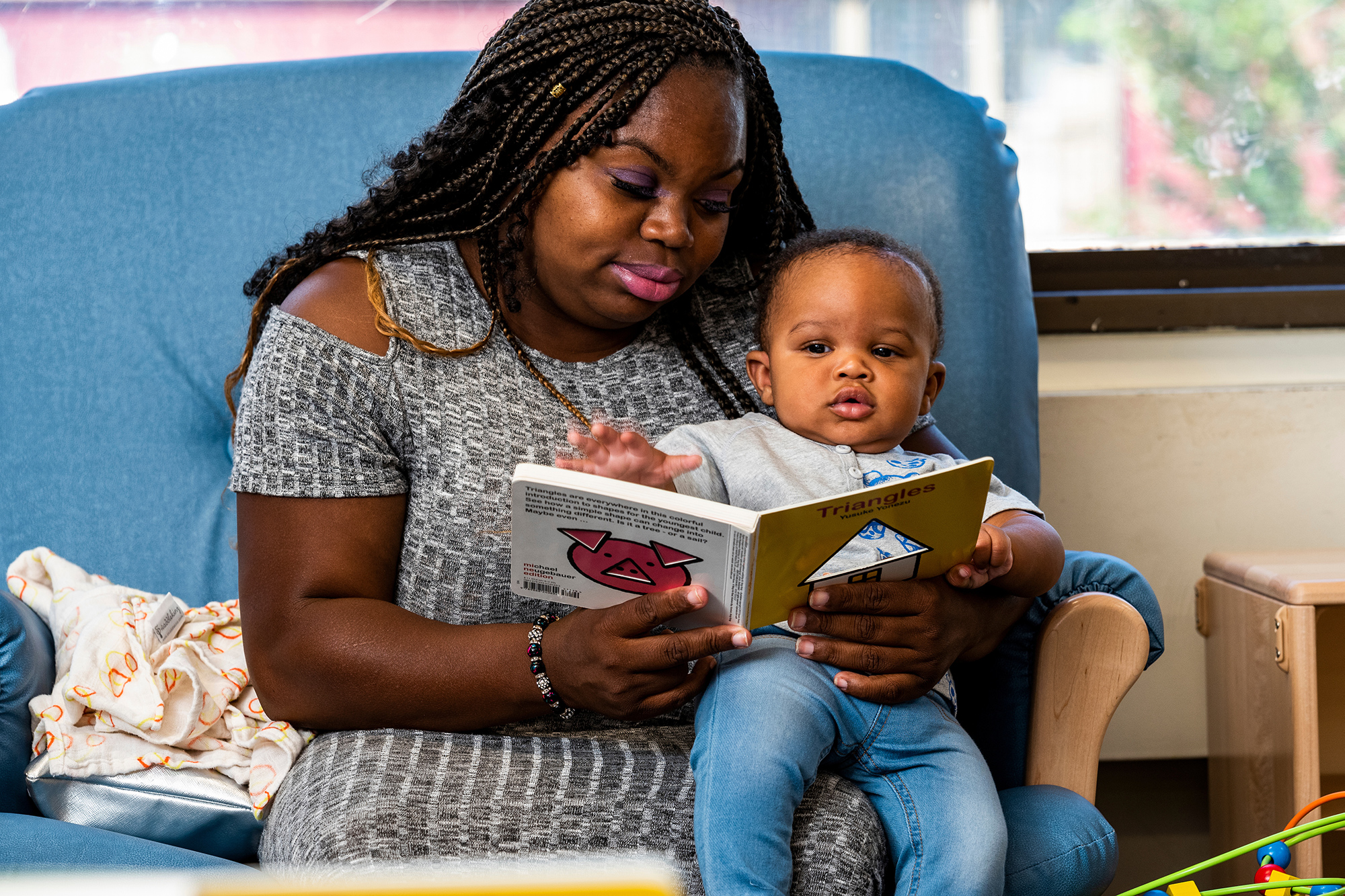 A woman reads a board book with a child on her lap. Photo by Chris Baker Evens.