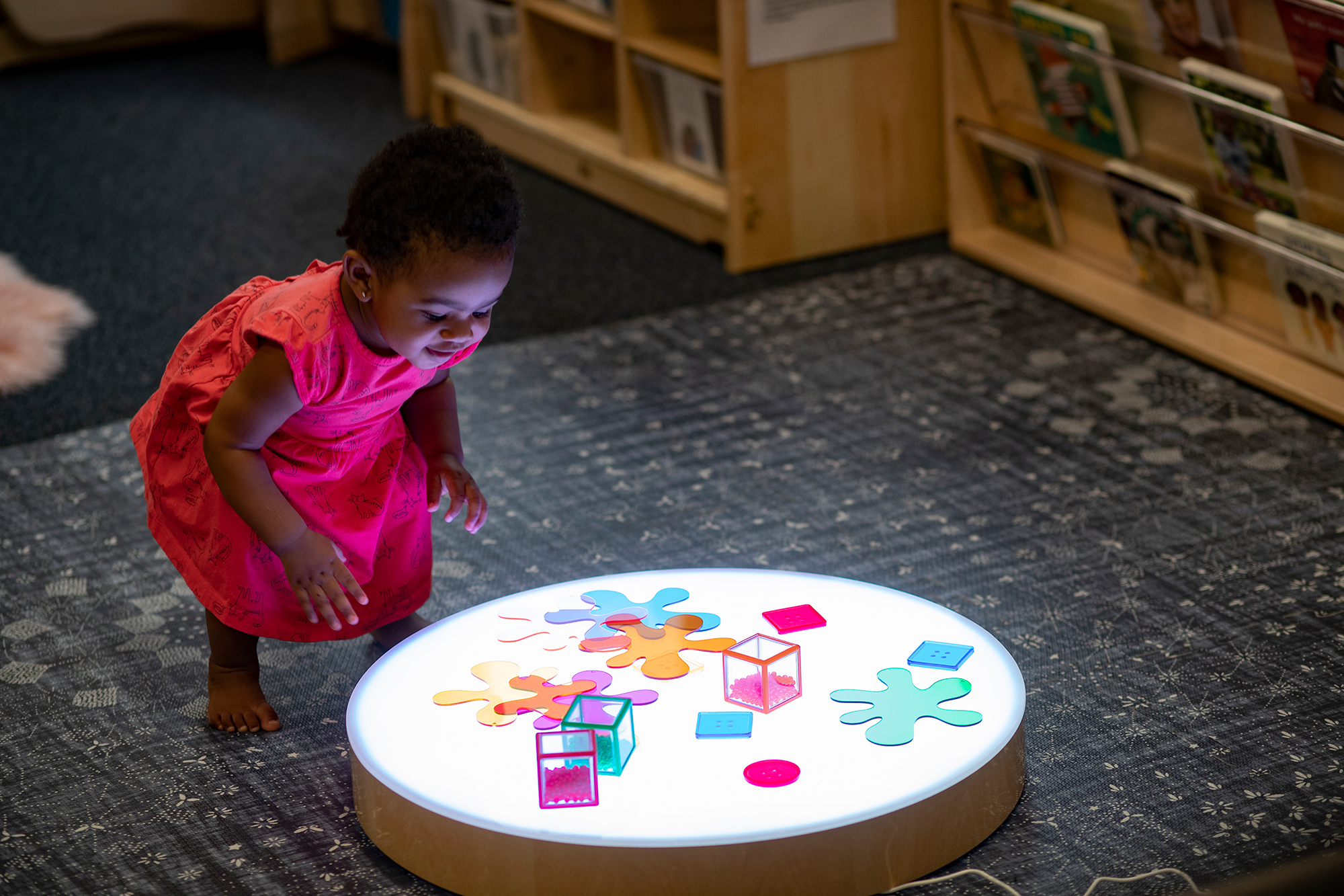 A child explores colorful items on a light table. Photo by Ryan Brandenberg.
