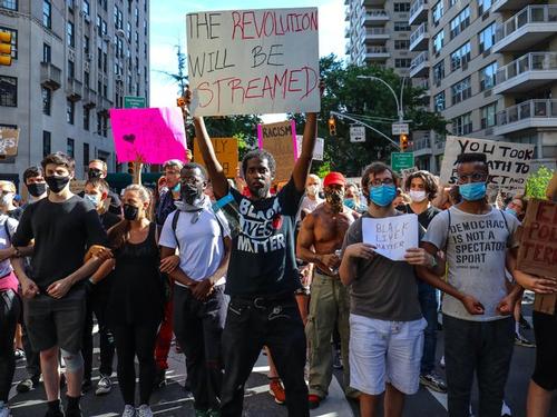 Photo of Black Lives Matter protest with a man holding a sign that says: The Revolution Will Be Streatmed