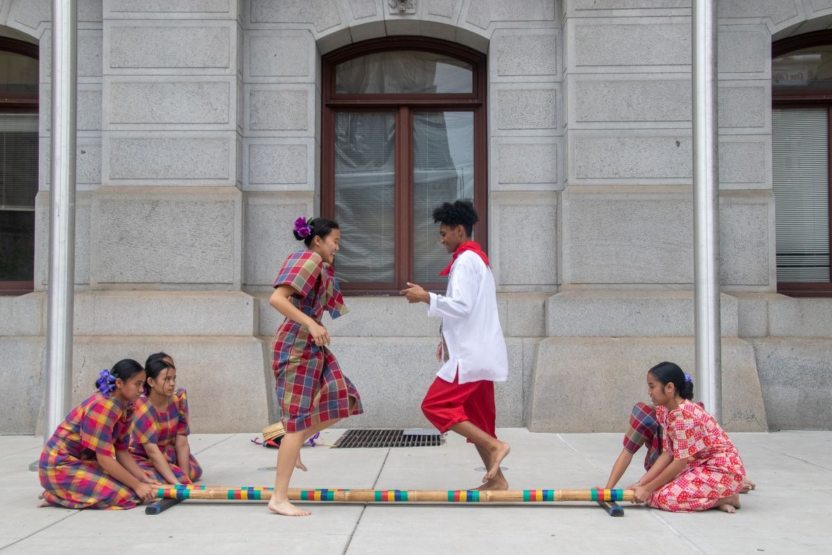 Young people performing Tinikling, a traditional Filipino folk dance, at RISE: A Love Letter to the AAPI Community at Philadelphia City Hall.