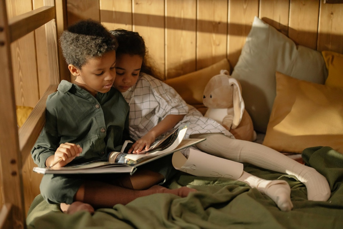 Two children cozy up to read a picture book together.