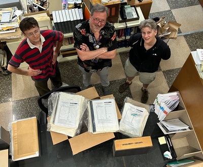 three staff members packing up piles of orchestral works