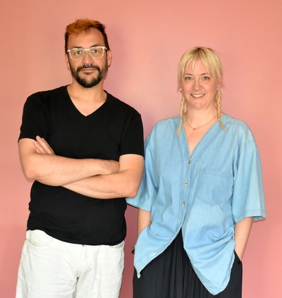 Man and woman standing in front of peach colored background