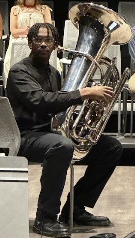 Young man holding a tuba about to play in an orchestral setting