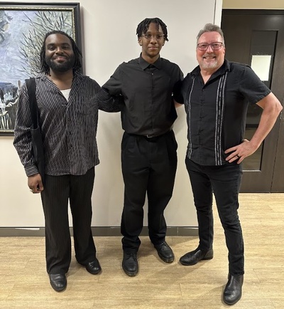 Three men posing and smiling for a picture all wearing balck