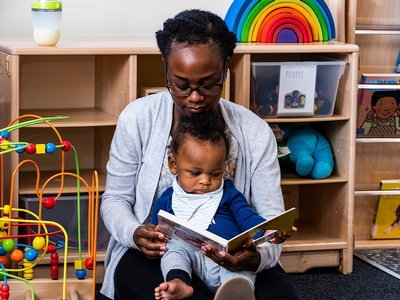 an adult reading to a baby in their lap